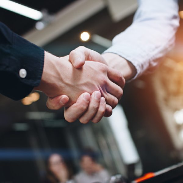 Bussines partners handshakes in modern open space on the background of coworking team on new startup project